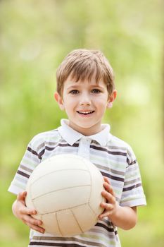 Little smiling child boy playing soccer sport ball outdoor