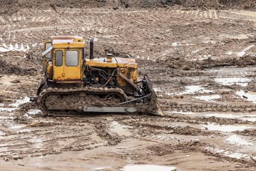 Old rusty earth digging caterpillar bulldozer machine working at building construction site