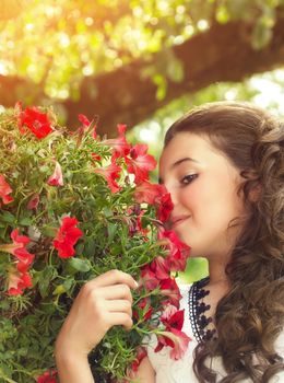 Beautiful little girl smelling flowers outdoor