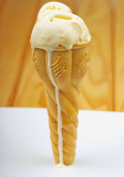 Ice cream cone with drop falling, over wooden background