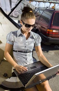 businesswoman has a fan with laptop in black car