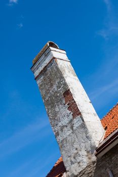 old brick chimney on orange tile roof (blue sky)