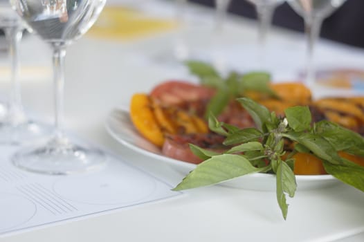 Closeup bunch of basil on plate of dishes with wine glass