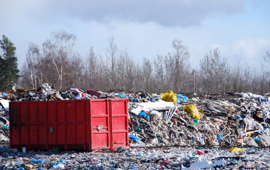 Red container full of waste in the trash dump