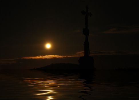 Island with a cross in the hopeless sea with the Moon reflecting in the water