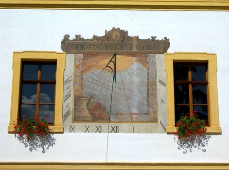           Sundial on the the wall between the windows. Measures time via shadow