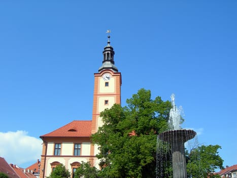       Church in Czech town Susice and fountain with tree