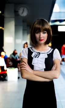 Brunette woman on railway station under clock