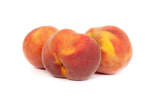 Three perfect, ripe peaches isolated on a white background.