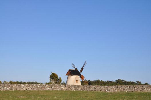 Old windmill by old stone wall in the country.
