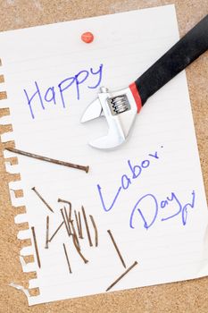 wrench and rusty nails with paper attach to cork board for labor day