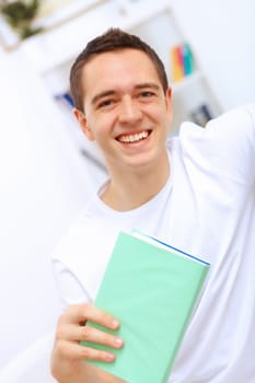 Young handsome man at home with a book