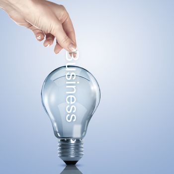 Hand putting a busines term into a light bulb