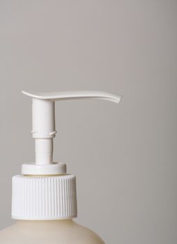 The top of a bottle of lotion isolated against a gray background