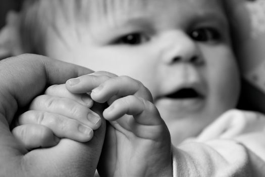 Infant grabbing on to dads hand. shallow depth of field focused on hands