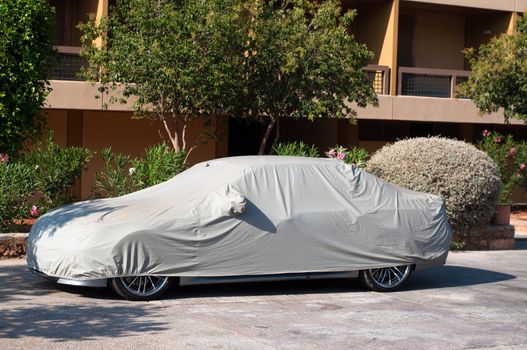 luxury car under soft cover garage in front of hotel building