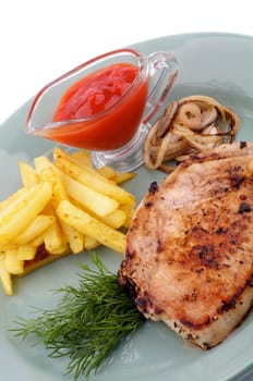 Pork Steak, French Fries and Grilled Onions with Ketchup and Dill close up on green plate