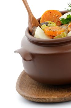 Hearty Vegetable Stew in Brown Pot on Wooden Plate with Spoon close up isolated on white background