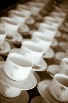 Many rows of pure white cup and saucer designed in vintage retro style. Note: the image contains grain as an element of style.