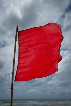 Red warning flag at a beach with storm clouds on background