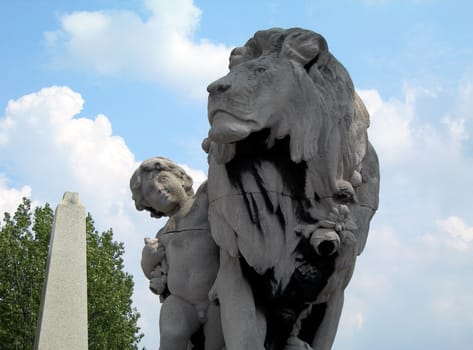 Boy petting the lion. Famous statue on the Bridge of Alexander III in Paris in France. 