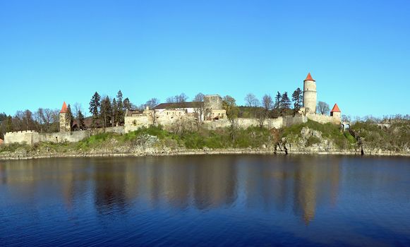 Old medieval czech castle with turrets, walls and a lake around it. 