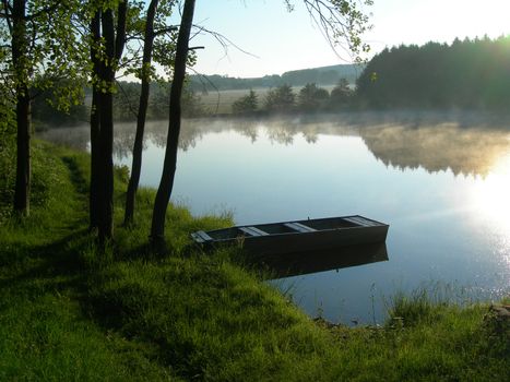  Pond during the sunrise with a old boat and mist         