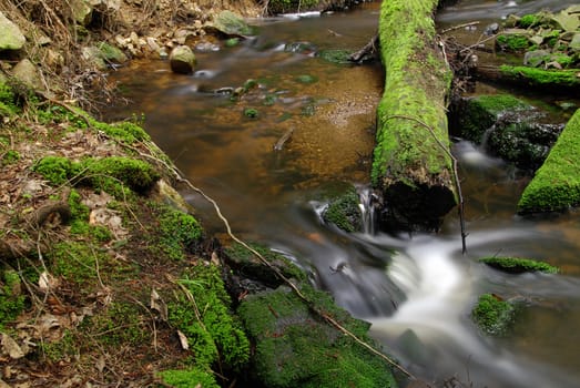 Hidden mountain brook with stones and moss with long exposure