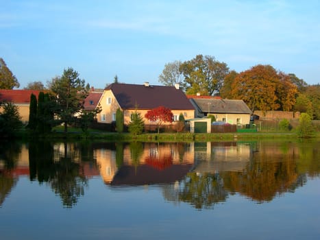         Autumn reflection of village in the river with colorful trees