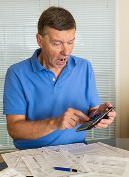 Senior caucasian man preparing tax form 1040 for tax year 2012  showing shock at amount of tax owed