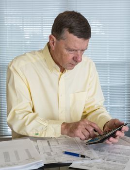 Senior caucasian man preparing tax form 1040 for tax year 2012  with receipts and calculator