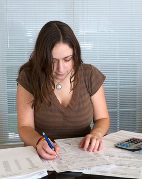 Young caucasian woman preparing tax form 1040 for tax year 2012  with receipts and calculator