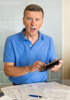 Senior caucasian man preparing tax form 1040 for tax year 2012  showing shock at amount of tax owed