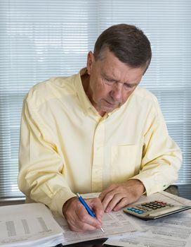 Senior caucasian man preparing tax form 1040 for tax year 2012  with receipts and calculator