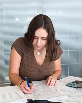 Young caucasian woman preparing tax form 1040 for tax year 2012  with receipts and calculator