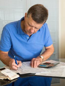 Senior caucasian man preparing tax form 1040 for tax year 2012  with receipts and calculator