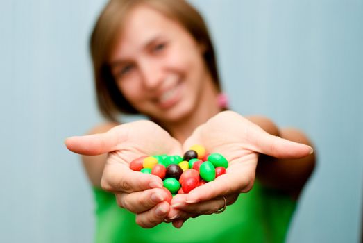 Portrait of a young woman offering colorful candies