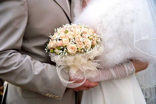 Bridal bouquet of white roses in hands of newlywed