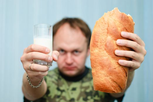 Portrait of a man in camouflage offering glass of milk and a loaf of bread