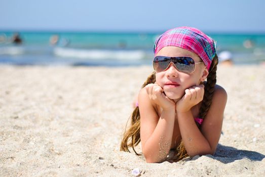 Little girl in sunglasses on the beach