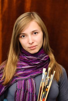 Portrait of young female artist with brushes