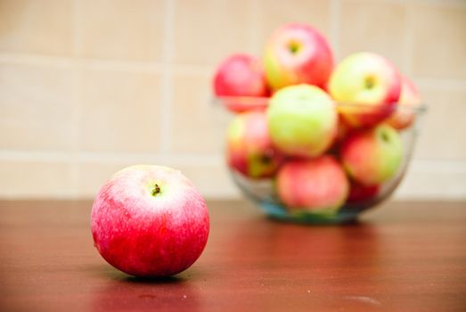 Juicy apple and blurred glass bowl filled with apples