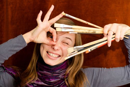 Funny portrait of young female artist with brushes