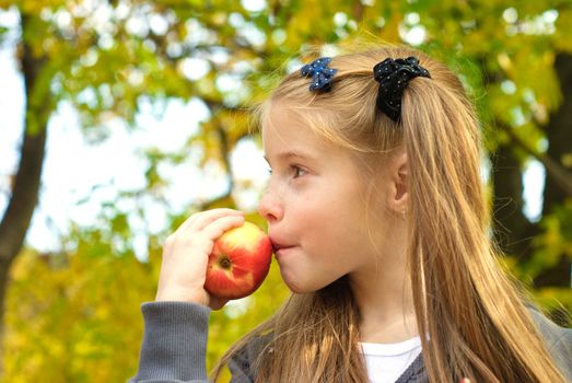 Little girl eating apple outdoors