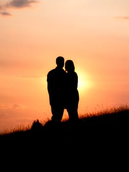 Couple standing on a hill at sunset