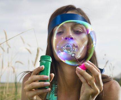 beauty young woman blowing soap bubbles in summer day