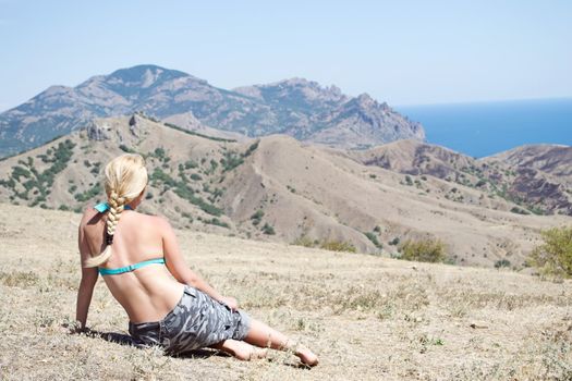 girl sitting, looking at the sea and the mountains