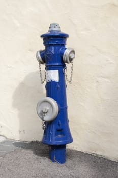 blue water hydrant at a white wall in germany
