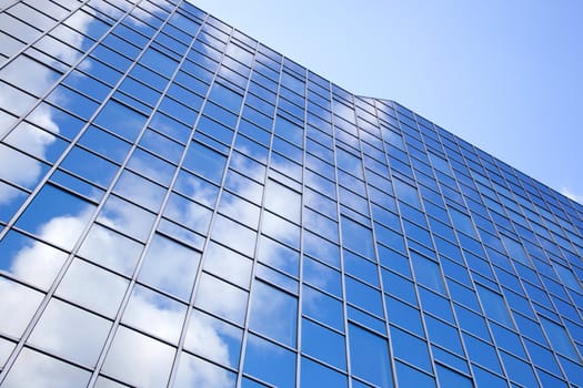modern facade of glass and steel reflecting sky and clouds