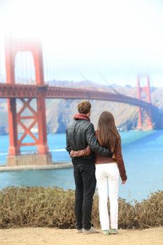 San Francisco Golden Gate Bridge. Young traveling couple enjoying view of the travel icon landmark and San Francisco Bay.